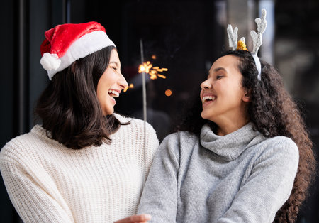 I will honor Christmas in my heart, and try to keep it all the year. Shot of two friends using a sparkle stick ay home.の写真素材