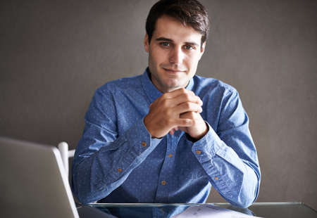 Yes, you could call me the head honcho. Portrait of a successful young businessman sitting at his...