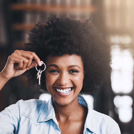 Beginning a new chapter of her life. Cropped shot of an attractive young woman holding house keys in her new home.の写真素材