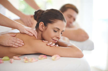Enjoying a day of pampering. A husband and wife lying receiving massages at a spa.