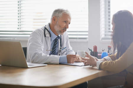 Dedicated to the health of his patients. Shot of a doctor meeting with his patient.の写真素材