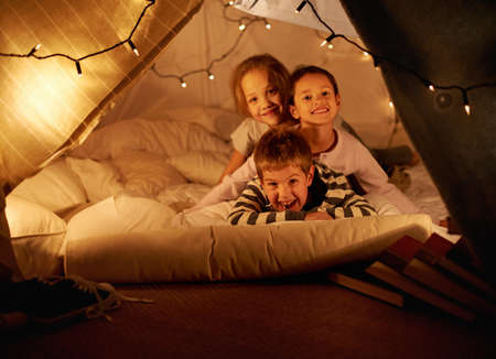 Blanket fort fun. Shot of three young children in a blanket fort.の写真素材