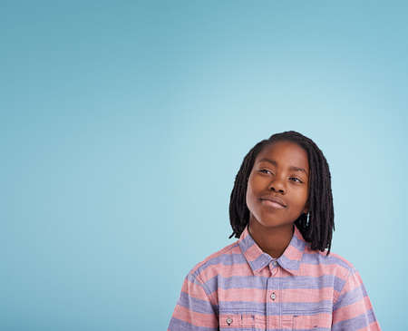 Putting his brain to work. Shot of a thoughtful young boy standing in studio.の写真素材