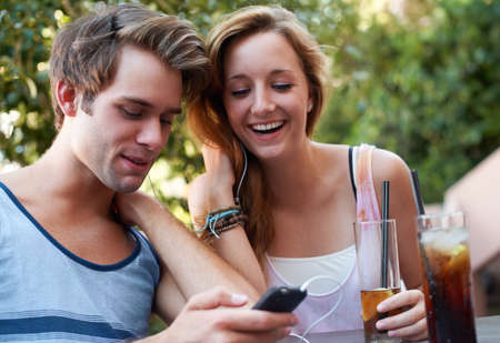 Socialising in the twenty first century. Cute teen couple sharing an MP3 player and listening to...