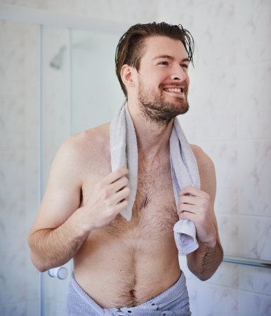 Feeling energised after a great shower. Cropped shot of a handsome young man wrapped in a towel after a shower.の写真素材
