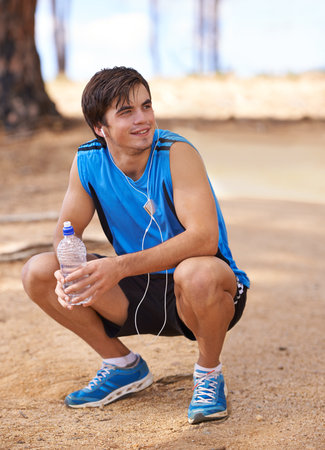 Theres nothing like fresh air and exercise. Shot of a handsome young man taking a break from exercising outdoors.の写真素材