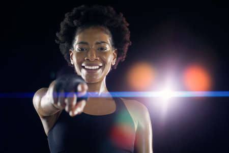 Studio shot of a young sportswoman posing with her finger pointed to the camera against a dark background.の写真素材