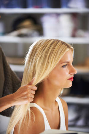 Behind the scenes prep. Pretty young woman having her hair done by a stylist.の写真素材