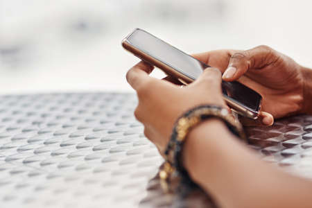 Just a text message away. Cropped shot of an unidentifiable woman using a smartphone at a table.