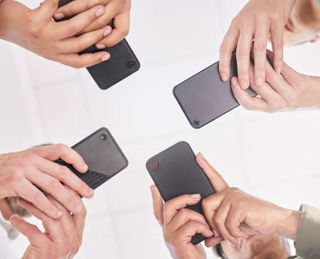 We need to know the group gossip. Shot of a group of coworkers together using their smartphones.