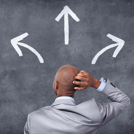 Make the right business choice. Conceptual shot of a businessman standing in front of a chalkboard with arrows on it.の写真素材