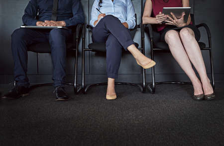 Ready and waiting. Cropped shot of three unrecognizable people sitting in line for an interview.の写真素材