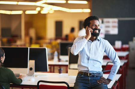 I knew Id heard from you. Shot of a confident businessman talking on his cellphone while standing in an modern office.の写真素材