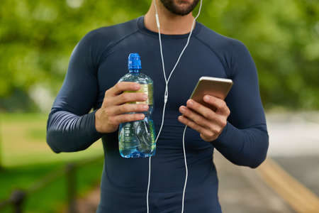 Equipped with water and his playlist. Cropped shot of an unrecognizable male runner taking a drink...