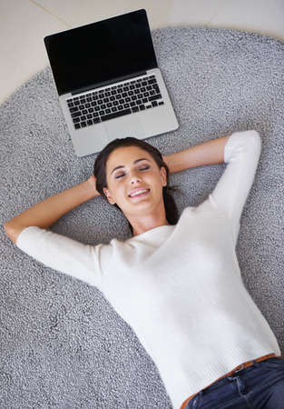 Letting my work worry about itself for a change. Shot of a young woman lying on a rug next to a...