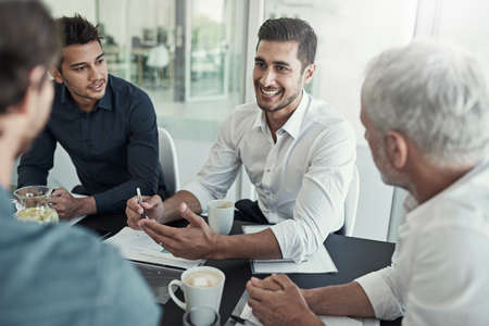Everyones feeling positive about this meeting. Shot of a group of businessmen having a meeting around a table in an office.の写真素材