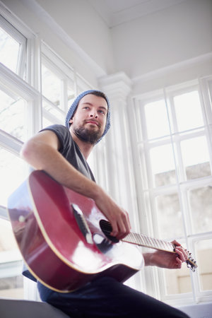 Mastering his musical skills. Cropped shot of a handsome young man playing a guitar at home.