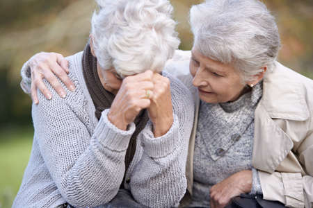 We are always there for each other. A senior woman consoling her friend as they sit outdoors.の写真素材
