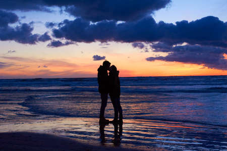 Nature setting the scene for romance. Silouehette of a couple kissing on the beach at sunset.の写真素材