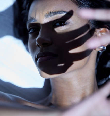 Im about to be blinded by this light. Shot of a young woman shielding her face from a bright light.