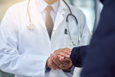 There is always hope. Cropped shot of a doctor holding a patients hand in comfort.の写真素材