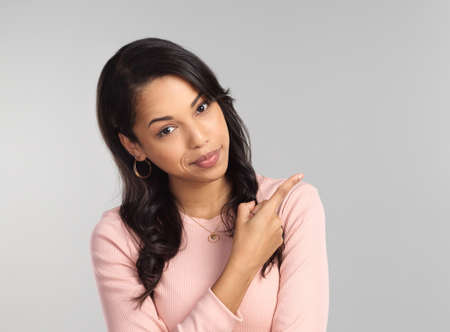 You know you want to.... Shot of a beautiful young woman pointing at copy space.