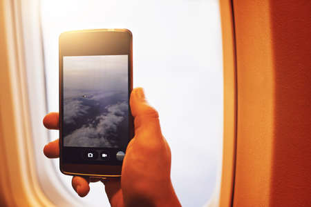 Capturing the view high above the clouds. Shot of a person taking a photo of the view through an...