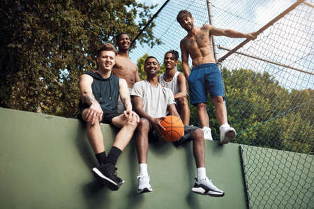 We feel right at home on the court. Portrait of a group of sporty young men hanging out on a basketball court.の写真素材