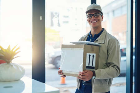 Your package has safely arrived. Portrait of a courier making a delivery.の写真素材