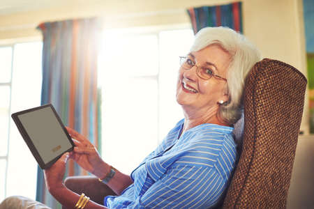 I can do everything from the comfort of my home. Cropped shot of a senior woman using a tablet at...