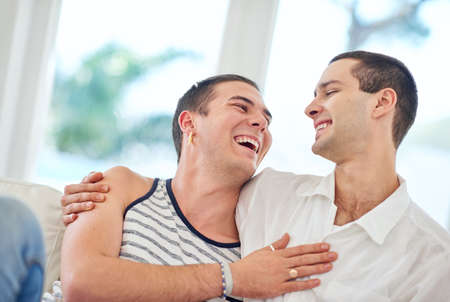 Our home is filled with love and laughter. Shot of a gay couple relaxing together at home.の写真素材