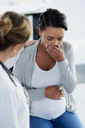 Everything will be alright. Shot of a confident female doctor trying to comfort a distressed pregnant patient at a hospital during the day.の写真素材