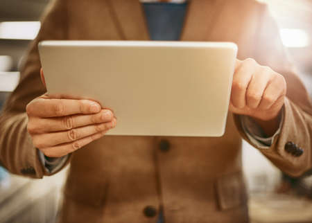 Digital design. Low angle shot of an unrecognizable male designer working on a tablet in his office.の写真素材