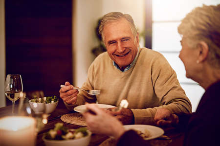 After all these years, theyve never run out of conversation. Shot of an elderly couple enjoying a meal and wine together at home.の写真素材