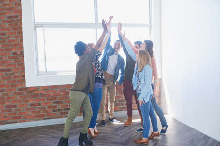 Achieving success together. Shot of a group of university students high fiving one another during class.の写真素材
