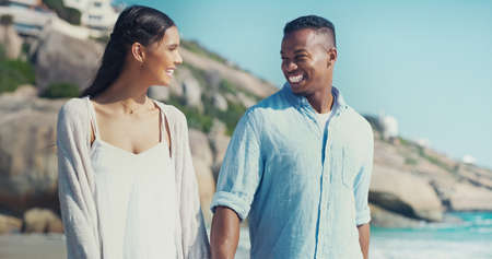 True love makes you smile. Cropped shot of a happy young couple walking together along the seashore.の写真素材