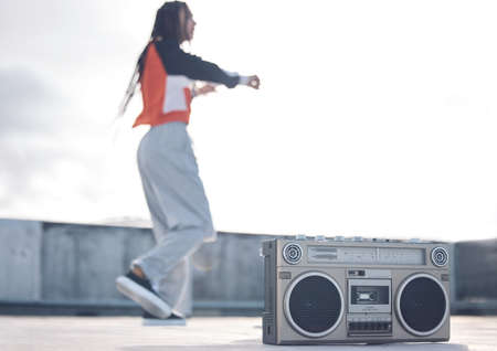 Move to the beat of your own drum. Shot of a young woman out on a rooftop with a boombox.の写真素材