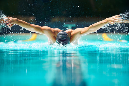 Perfect butterfly stroke. Shot of a male swimmer doing the butterfly stroke toward the camera.の写真素材
