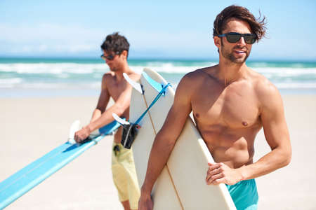 Surfs up. Two friends at the beach getting ready to head into the water for a surf.の写真素材