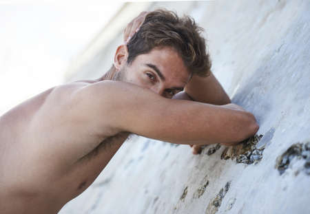 Posing for the camera. Portrait of a handsome young man leaning against a rock.の写真素材