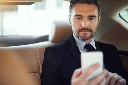 Scheduling appointments on the go. Cropped shot of a businessman using his cellphone while sitting...