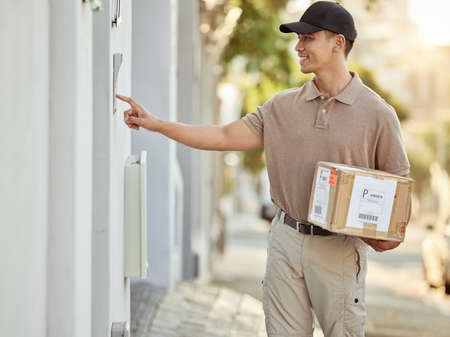 I finally found the house. Shot of a delivery man about to drop off a package.の写真素材