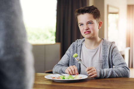 Id rather go to bed hungry. Shot of a young boy refusing to eat his brussels sprouts at home.の写真素材