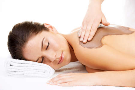 Discover the miraculous effects of mud. Cropped shot of a young woman getting a beauty treatment isolated on white.の写真素材