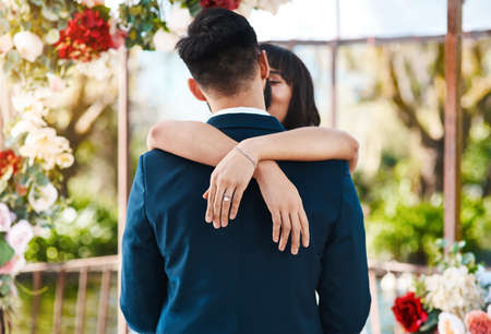 The groom is hers to smooch. Cropped shot of an affectionate young bride kissing her groom while her hands are wrapped around him on their wedding day.の写真素材