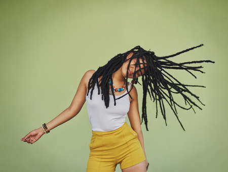 Forget ordinary, live for the extraordinary. Shot of an attractive young woman dancing against a green background.の写真素材