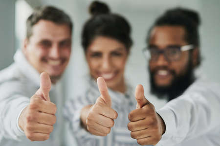 Business never looked better. Portrait of a group of businesspeople showing thumbs up in an office.の写真素材