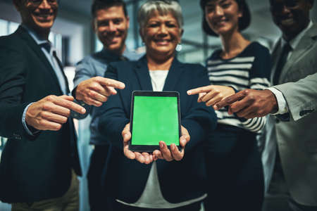 Its all happening online. Shot of a group of businesspeople pointing to a digital tablet with a...