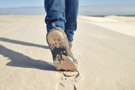 No climate is too much. Shot of a young male hiker walking along the sand dunes.の写真素材