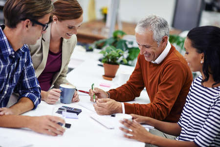 A bit of fun in the morning meeting. A cropped shot of a group of professionals having a meeting at...